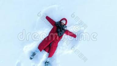 穿着红色羽绒服的女孩做了个雪天使。 空中，摄影机以螺旋上升，俯视