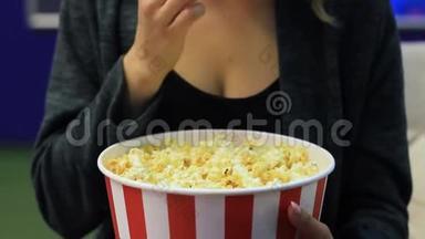 无法辨认的女人在电影院吃爆米花。