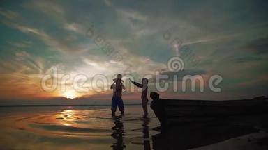 日落时分，家人在湖边玩耍。 小朋友和<strong>家长</strong>的剪影们下一在一起，跑步和玩耍。 慢慢