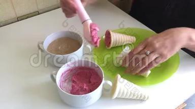 一个女人在喇叭里加了草莓冰淇淋。 用冰淇淋勺。 放在盘子上。 桌子上有集装箱和