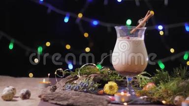 节日餐桌，一个漂亮的玻璃杯，传统的鸡蛋鸡尾酒，装饰着圣诞树和彩灯，蛋酒
