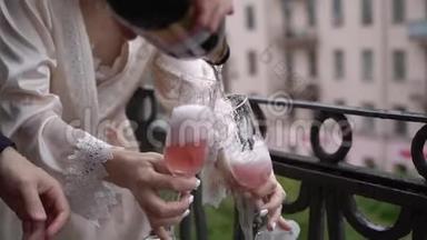 年轻夫妇打开一瓶香槟，在阳台上倒入玻璃杯。 酒精饮料和饮料。