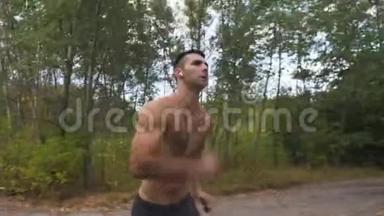 初秋，带着无线耳机的英俊的肌肉男在森林附近的小径上快速冲刺。 运动员