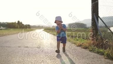 夏天，漂亮的孩子在田野附近玩耍。 一个小男孩沿着马路跑。