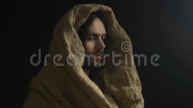 上帝的儿子，穿着长袍的耶稣基督在黑暗的背景上看着摄像机