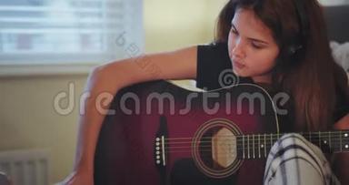 一位年轻女士在房间里用吉他弹奏的特写镜头，很奇怪，她用笔记本拿了一些