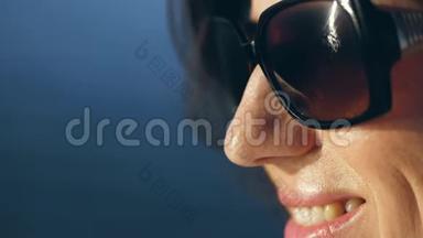 肖像，一个戴太阳镜微笑的女人的轮廓。 阳光反射在眼镜里。 在蔚蓝的大海上