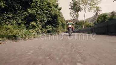 骑摩托车的人在棕榈树背景下的乡村道路上驾驶摩托车。 高级摩托车骑手