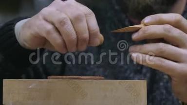一位工匠用木刀切下一圈均匀的粘土，用宜兴粘土做茶壶盖。手工陶制茶壶