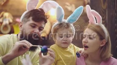 画复活节彩蛋的家庭的特写。 母亲，父亲和他们的儿子画复活节彩蛋。 准备复活节