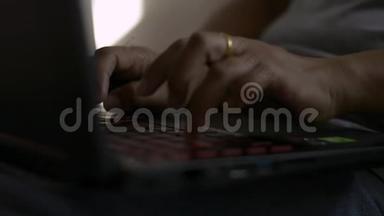 女人的手在床上的电脑键盘上打字。
