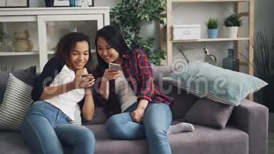 活泼开朗的亚裔和非裔美国人会谈笑风生地看着智能手机屏幕上的小玩意