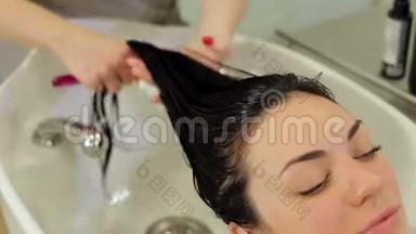 美发师给女孩的头发戴上保湿油`面膜。