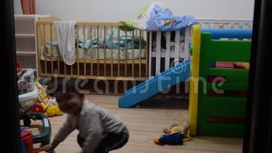 儿童在室内玩耍的时间推移。 两岁的男孩在塑料滑梯上滑，而婴儿在步行者中玩耍