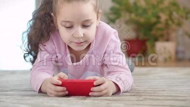 可爱的婴儿用手机或平板电脑娱乐。 小女孩把空闲时间花在玩手机游戏上，玩得很累