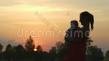 <strong>夕阳</strong>的剪影：年轻的母亲抱着她的小男孩在城市公园站在<strong>夕阳</strong>面前，生动活泼