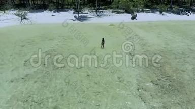 在菲律宾白沙滩和绿松石水中间的女人身上站着的无人机