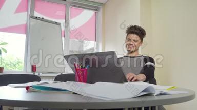 年轻的男大学生微笑着在笔记本电脑上打字