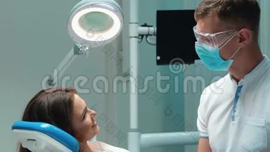 <strong>年</strong>轻英俊的牙医戴着蓝色的医用手套、<strong>口罩</strong>和眼镜，与深褐色皮肤的病人讨论女人的过程