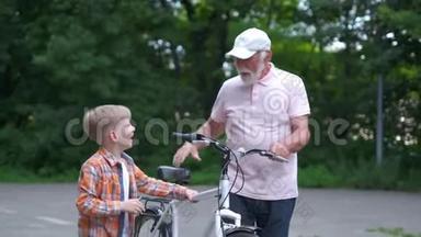 快乐爷爷教男孩如何在夏天公园骑自行车。 家庭、世代、安全和人的概念