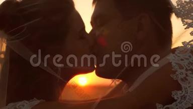 年轻的已婚夫妇在日落时<strong>亲吻</strong>和拥抱。 特写镜头。 一对相爱的情侣在夕阳下的<strong>剪影</strong>