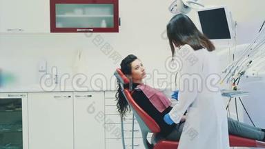 牙医和病人。 年轻漂亮的牙医在牙医`办公室修理一位漂亮年轻女子的牙齿。 牙医