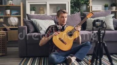 帅哥vlogger正在录制视频，供订户教学，用吉他演奏乐器和