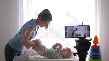 孕产妇保健，著名博主妈妈在手机上录制视频课时，给婴儿换衣服