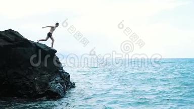 一个年轻人从悬崖上跳进<strong>蓝色</strong>的大海。 活跃有趣的暑假..
