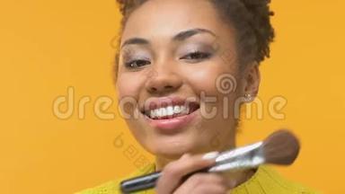 微笑的非洲女人用化妆刷，美容趋势，时尚