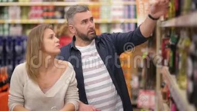 美丽的年轻夫妇在超市度过时光。 家庭有很多乐趣从超市挑选葡萄酒