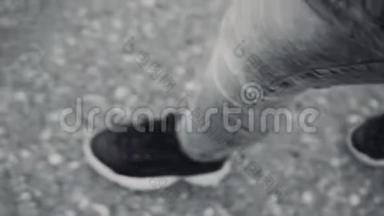 穿运动鞋的女人`脚的黑白镜头。 女孩在城里走来走去。