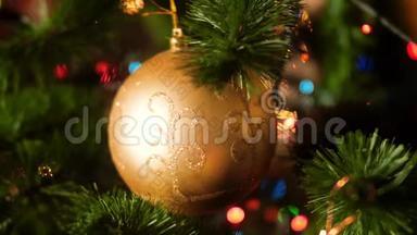 特写4k<strong>视频</strong>，金色闪闪发光的宝珠挂在<strong>圣诞树</strong>上，与五颜六色的闪烁和发光的灯光和