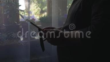 一位老年妇女的特写肖像站在窗口，拿着一个相框和你的照片，看着它。