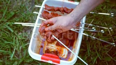 一个人用扦子把生肉推了过去。 户外烹饪烤肉串