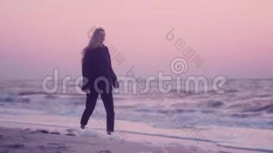 日出时，美丽的女孩走在海滨潮湿的沙滩上
