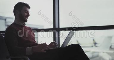 一个年轻人在机场候机区用笔记本电脑工作的画像，然后他关上笔记本电脑，走向