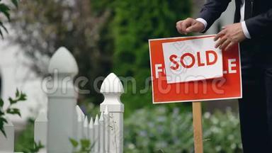 房地产经纪人把出售的铭文放在出售的<strong>招牌</strong>上，交易成功