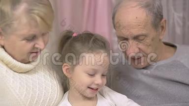 祖父和祖母正在读一本书，他们的孙女坐在家里的沙发上，家庭<strong>价值观</strong>
