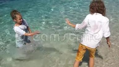 两个学生穿着衣服在海水中玩耍。 快乐的孩子们泼水