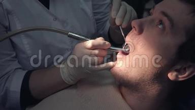 一位戴着无菌口罩和衣服的牙医用医疗器械在病人口`做手术
