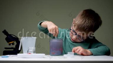 戴眼镜的男孩在做实验。 年轻的科学家把地衣混合起来做实验。 学龄前儿童在室内玩耍。 家庭