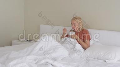 一个女人，一张悲<strong>伤痛</strong>苦的脸，坐在白色毯子下的床上，吃着一盘汤。