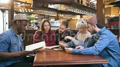 一群年轻的朋友在酒吧、酒吧里阅读菜单，选择点菜。