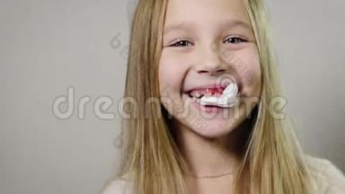 一个可爱的微笑女孩的肖像特写，一个嘴里拿着白色餐巾的孩子，牙龈出血，下巴出血。 牙齿流失