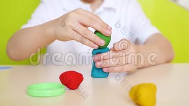 一个孩子在餐桌上玩得很开心，特写镜头，在五颜六色的粘土或面团<strong>模型</strong>中玩<strong>游戏</strong>
