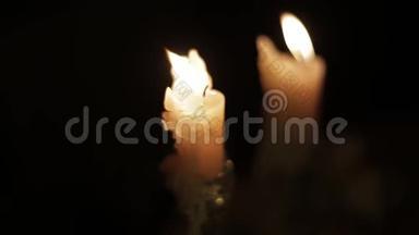 在黑暗的房间里近距离观看明亮燃烧的蜡烛。 在黑暗中点燃蜡烛，温暖舒适的气氛