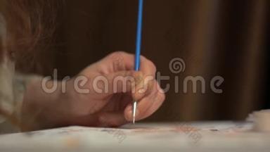 女孩用蓝色的细流苏在画布上作画