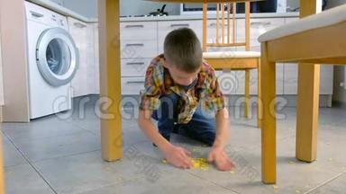 男孩用手清理厨房地板上的玉米片。
