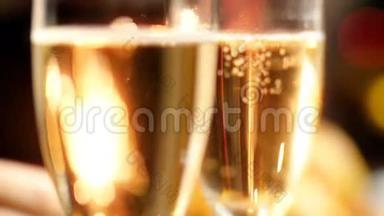 在圣诞节的夜晚，两个装满香槟的杯子在燃烧的火花中的特写慢动作视频。 完美完美完美